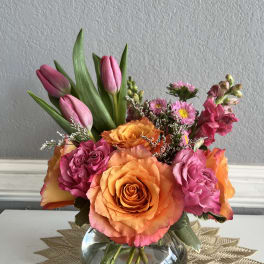 Pink tulips and orange roses arranged in a glass vase