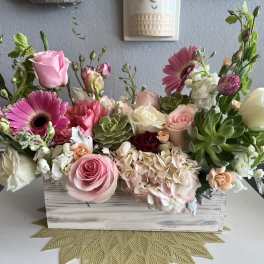 Pink and white floral arrangement in a wooden box with succulents