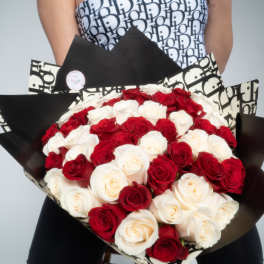 Large hand-tied bouquet of red and white roses wrapped in black and cream graphic paper.