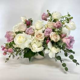 Pastel rose bouquet in a white vase with trailing greenery