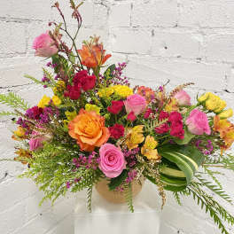 Colorful mixed bouquet of roses and small filler flowers in a round vase