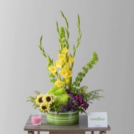 Yellow gladiolus and sunflowers in a striped green container