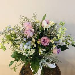 Bouquet of pink and lavender roses with white flowers in a glass vase