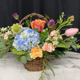 Basket arrangement with blue hydrangea, roses, tulips, and carnations