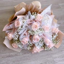 Bouquet of pale pink roses with white baby's breath in blush and beige wrap