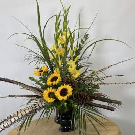 Tall arrangement of yellow flowers and sunflowers in a black vase