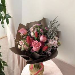 Pink and red mixed bouquet wrapped in dark paper