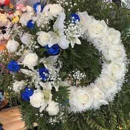 Large floral wreath of white roses, lilies, and blue roses