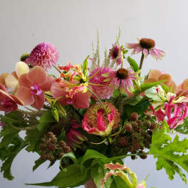 Loose bouquet of pink and peach orchids, dahlias, and mixed flowers with berries.