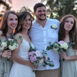 Wedding party holding white and pink bouquets at sunset