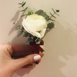 Small white flower boutonniere with greenery and a burgundy ribbon