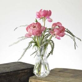 Pink flowers in a clear glass vase with airy greenery