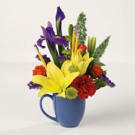 Bouquet of yellow lilies, purple irises, and red roses in a blue mug