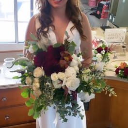 Bride holding a large bouquet of white and burgundy flowers