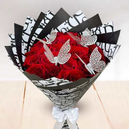 Bouquet of red roses wrapped in black-and-white paper with butterfly accents
