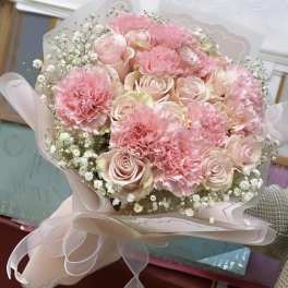 Pink roses and carnations in a wrapped bouquet with baby's breath