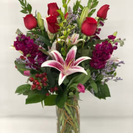 Tall bouquet of red roses and pink lilies in a glass vase