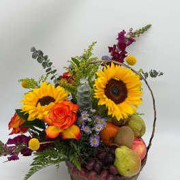 Basket arrangement with sunflowers, roses, grapes, and assorted fruit