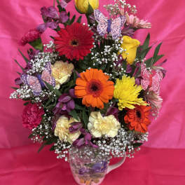 Colorful mixed flower bouquet in a floral mug with butterfly picks