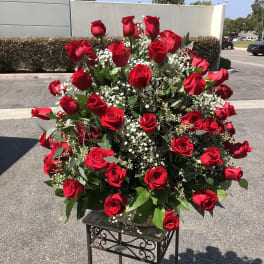 Large arrangement of red roses with baby's breath on a stand