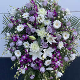 Large standing floral spray with white lilies, lavender roses, and purple orchids