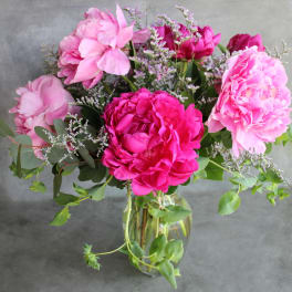 Pink peonies arranged in a clear glass vase with airy filler flowers