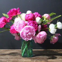 Pink and white peonies in a green glass vase
