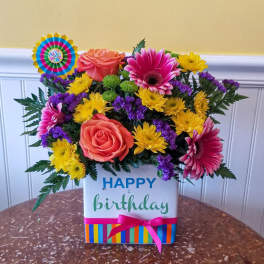 Birthday flower arrangement in a decorated gift box with a ribbon
