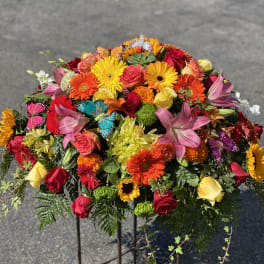 Colorful mixed flower arrangement on a stand with roses, gerbera daisies, lilies, and butterflies