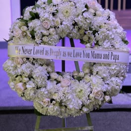 White floral wreath on an easel with a memorial ribbon