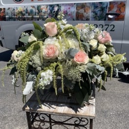 Large bouquet of pale pink and white roses with greenery on a table