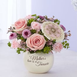 Pink rose bouquet in a cream vase with a decorative plaque