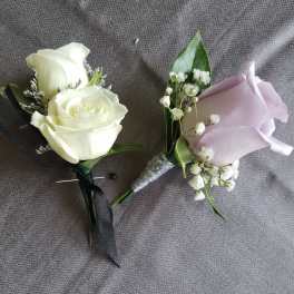 Pair of white and lavender rose boutonnieres with baby's breath and black and silver ribbon accents