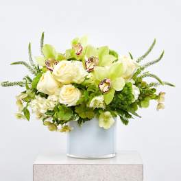 Green and white floral arrangement in a glass vase