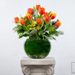 Orange and yellow tulips in a green glass vase