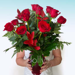 Red roses arranged in a burgundy vase with greenery