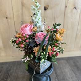 Pink roses and mixed flowers arranged in a dark vase