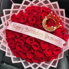 Heart-shaped bouquet of red roses with a birthday ribbon and crown decoration