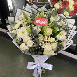 White bouquet with roses, chrysanthemums, and lilies wrapped in paper