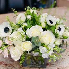 White roses and anemones arranged in a glass vase