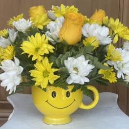 Yellow and white flowers in a smiley-face mug vase