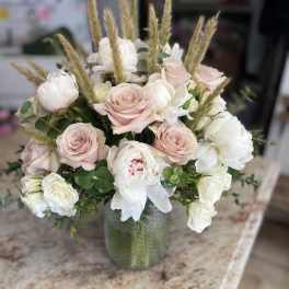 Blush and white rose bouquet in a green glass vase