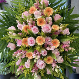 Pink roses and peach gerbera daisies in a large standing arrangement