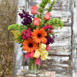 Bright mixed bouquet in a glass vase with orange daisies and pink roses