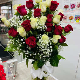 Bouquet of red and white roses in a glass vase with a white ribbon