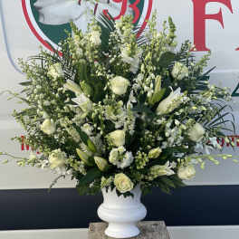 Large white floral arrangement in a white urn vase