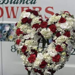 Heart-shaped floral wreath of red and white flowers on a stand