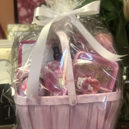 Pink gift basket wrapped in clear cellophane with a white ribbon