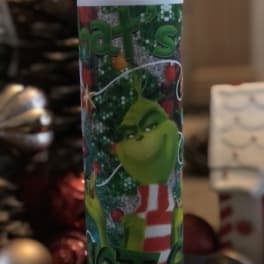 A tall holiday tumbler with the Grinch and Christmas graphics.