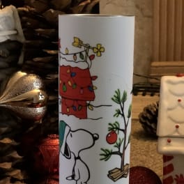 Holiday candle with a Snoopy and Christmas tree design